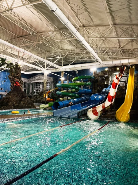 Khmelnytsky, Ukrayna - 10 Kasım 2025: Renkli slaytlarla dolu açık bir kapalı su parkı ve aile eğlencesi ve rahatlığı için dolambaçlı bir havuz.