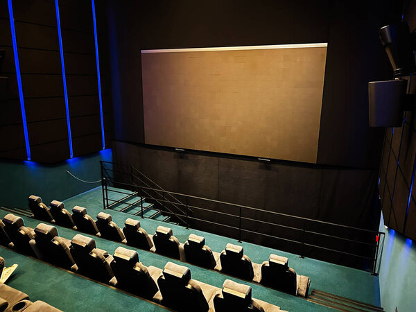 Kyiv, Ukraine - November 10, 2025: An empty theater style cinema with a large screen, tiered seats, and moody blue lighting.