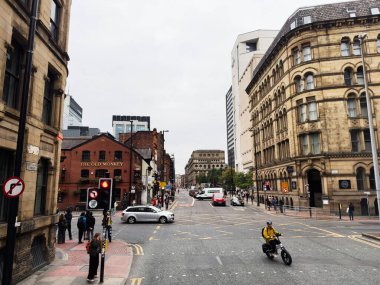 Manchester, İngiltere - 30 Eylül 2025: Tarihi taş binalar, yayalar, arabalar ve yaya dostu bir kavşakta bir motosiklet sürücüsüyle dolu Manchester Portland caddesi.