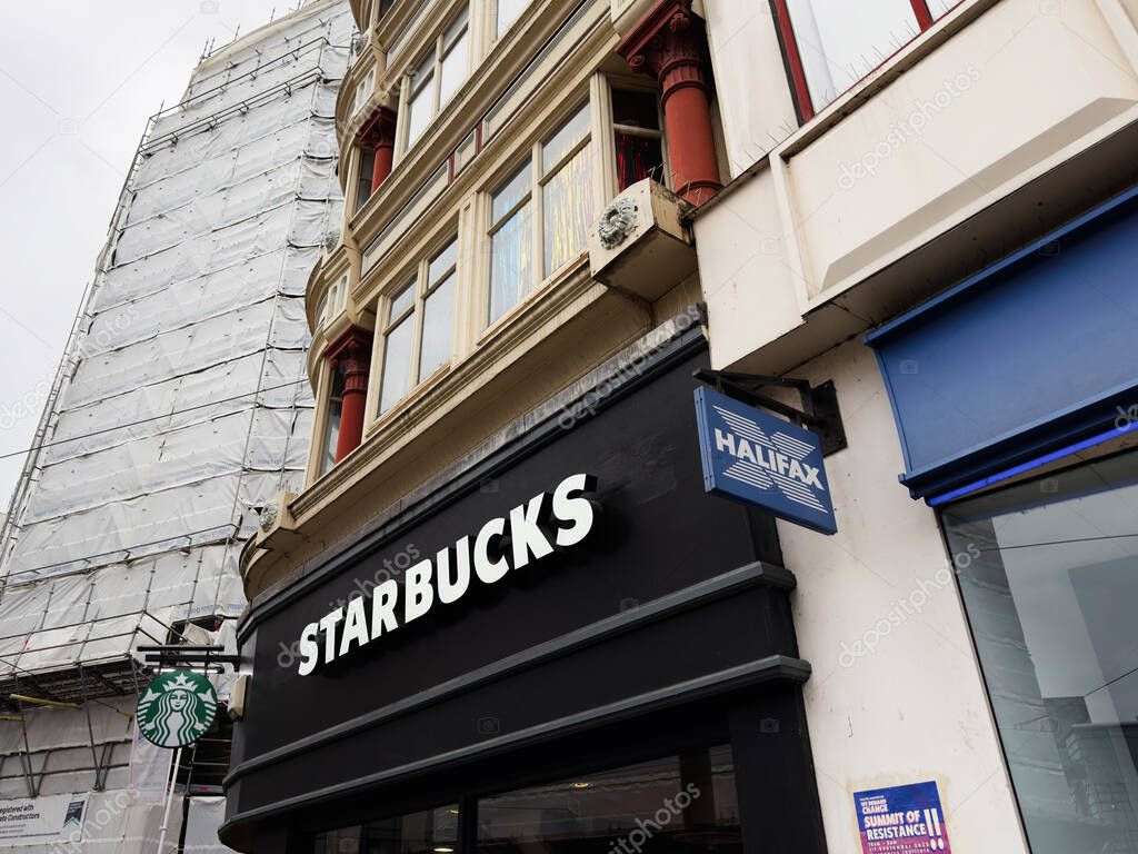 Manchester, UK - September 30, 2025: Starbucks exterior in Manchester, UK, with Halifax sign on a historic building and urban storefront.