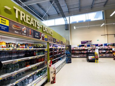 Manchester, İngiltere - 30 Eylül 2025: Bright Manchester Tesco süpermarket iç mekanı, içki ve abur cubur reyonu ve dergi bölümü.