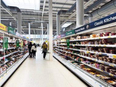 Manchester, İngiltere - 30 Eylül 2025: Müşteriler Manchester 'da hazır yemeklerle dolu bir süpermarket koridorunda yürüyorlar.