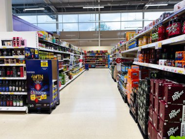 Manchester, İngiltere - 30 Eylül 2025: Manchester 'da parlak raflarda içeceklerle dolu Vibrant UK süpermarket koridoru, müşteriler görünmüyor, alışveriş sahnesi davet ediliyor.