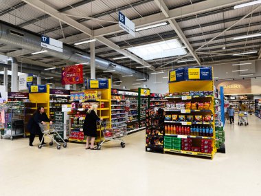 Manchester, İngiltere - 30 Eylül 2025: Manchester süpermarket içi alışveriş arabalarını renkli vitrinlerden ve koridorlardan geçiren müşterilerle dolu.
