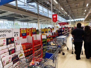 Manchester, İngiltere - 30 Eylül 2025: Manchester 'da bir mağazadaki müşteriler çıkış kasaları yakınlarındaki tebrik kartları ve bakkallara bakıyorlar.