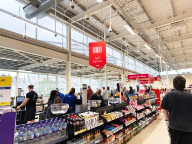 Manchester, İngiltere - 30 Eylül 2025: Manchester mağaza sahnesi self servis kasasında müşteriler ve raflar dolusu atıştırmalıklarla dolu.