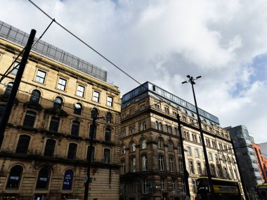 Manchester, İngiltere - Ekim 04, 2025: Süslü cepheleri, tramvay hatları ve şehir manzaralı sarı bir otobüsü olan Manchester Caddesi.