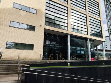 Manchester, İngiltere - Ekim 04, 2025: Manchester 'da görkemli girişi, basamakları ve rampası olan modern tuğla ve cam ofis binası.