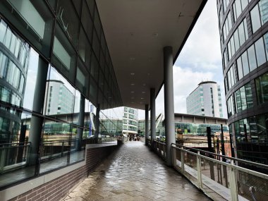 Manchester, İngiltere - Ekim 04, 2025: Manchester 'da örtülü bir gölgelik altında cam duvarlı ofislerin yanında gösterişli bir yaya yolu