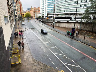 Manchester, İngiltere - Ekim 04, 2025: Yağmurlu Manchester sokak sahnesi yayalar, otobüsler, arabalar ve çağdaş mimari.