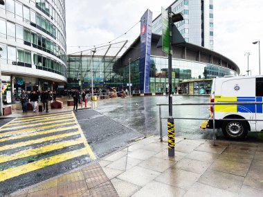 Manchester, İngiltere - Ekim 04, 2025: Manchester, İngiltere 'de yayalar ve araçlar, cam binalar ve bir tramvay istasyonu yakınlarındaki modern Manchester Piccadilly taşıma merkezini çevrelemektedir..