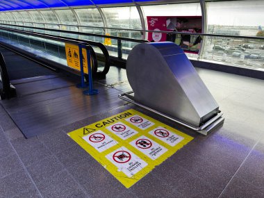 Manchester, UK - October 04, 2025: Escalator area in a Manchester transit airport station featuring yellow caution signs and sleek metal design.