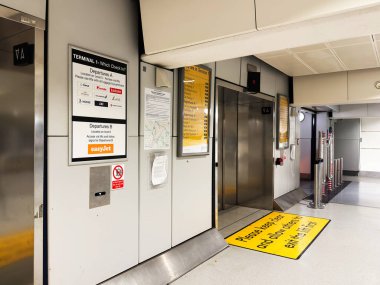 Manchester, UK - October 04, 2025: Inside Manchester airport terminal, signs guide departures and check in with elevator and safety floor markings.
