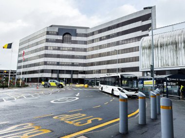 Manchester, UK - October 04, 2025: A bustling airport transport hub beside a sleek municipal building in Manchester, showcasing buses, signage, and traffic.