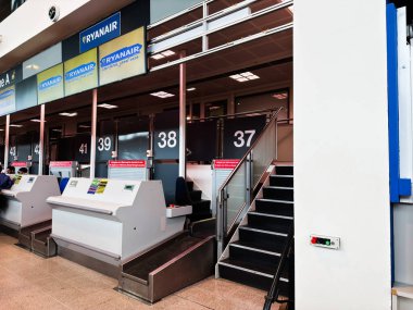 Manchester, UK - October 04, 2025: Busy Manchester airport scene showing Ryanair checkin counters and stairs near numbered bays 37 to 43.
