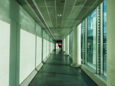 Manchester, İngiltere - Ekim 04, 2025: Manchester 'da sakin bir koridor boyunca cam pencereleri ve uzak yolcuları olan parlak modern iç mekan.