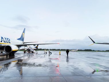 Manchester, İngiltere - Ekim 04, 2025: Islak Manchester önlüğündeki Ryanair uçağı yer ekibi ve yolcuları uçağa binmeye hazırlanıyor.