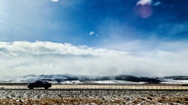 Yalnız bir kamyonet Utah 'ta karla kaplı bir otoyolda, dağlarda ve açık gökyüzünde seyahat eder..