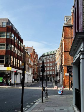 Londra, İngiltere - 22 Eylül 2025: Sessiz bir Londra Büyük Peter caddesi tuğla binalar, dükkan önleri ve açık mavi gökyüzü altında bisikletler.