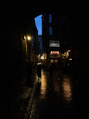 Londra, İngiltere - 22 Eylül 2025: Ilık ışıkların altında parlayan ıslak kaldırımların olduğu karamsar bir Londra sokak manzarası. Clink Hapishanesi Müzesi