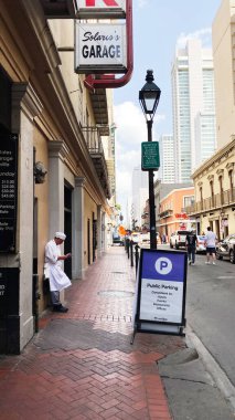 New Orleans, Louisiana, ABD - 15 Mart 2025 Solaris 'in Otoparkı' nın önünde bir şefin ve halka açık bir park levhasının yer aldığı canlı bir New Orleans sokak sahnesi.