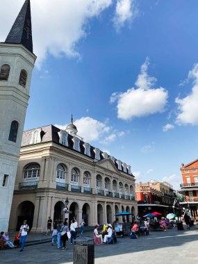 New Orleans, Louisiana, ABD - 15 Mart 2025: Tarihi bir bina, kilise kulesi ve hareketli pazar tezgahları ile New Orleans meydanı.