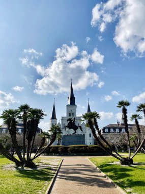 New Orleans, Louisiana, ABD - 15 Mart 2025 Palmiye ağaçları ve tarihi bir katedralin çerçevelediği güneşli New Orleans plazasında bronz binici heykeli.
