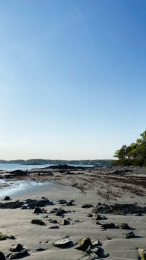 Huzurlu Portsmouth plajı kayalar, gelgit havuzları ve alacakaranlıkta açık mavi bir gökyüzü..