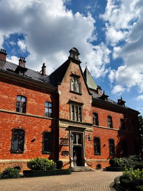 Krakow, Polonya - 19 Temmuz 2025 İlahi Merhamet Tapınağı 'nın kırmızı tuğlalı cephesi dekoratif kapısı, demir pencereleri ve iyi korunmuş yeşilliği olan tarihi Polonya binası.