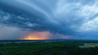Güney Illinois 'in düzlüklerinde dramatik fırtınalı bir gökyüzü turuncu günbatımı ufukta parlarken.