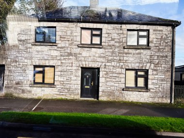 Longford, İrlanda - 21 Ekim 2025 İrlanda 'da siyah giriş kapısı ve birden fazla penceresi olan gri taştan iki katlı bir ev.