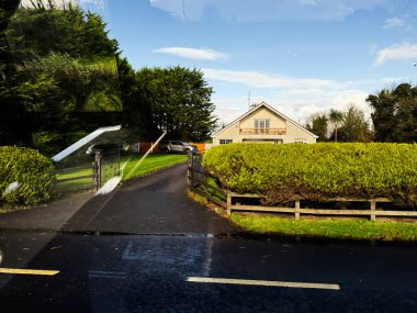 Longford, İrlanda - 21 Ekim 2025: İrlanda 'da bir ev, çit, kapı, araba ve ıslak yansıtıcı yol gösteren parlak banliyö manzarası.