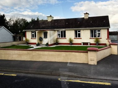 Curraghmore, İrlanda - 21 Ekim 2025: Düzenli çimleri, saksı bitkileri ve karşılama girişi olan tuhaf bir İrlanda evi.