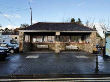 Castlerea, İrlanda - 21 Ekim 2025: İrlanda 'da sıraları, taş duvarları ve açık gökyüzü olan bir İrlanda köyünde konforlu otobüs durağı.