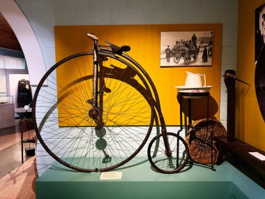 Tık, İrlanda - 22 Ekim 2025: Sarı arkaplan, çaydanlık ve klasik fotoğrafların yer aldığı bir müzede tarihi bisiklet sergisi.