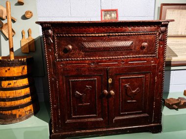 Tık, İrlanda - 22 Ekim 2025: oyulmuş kuş panelleri ve demir donanım ile süslü koyu ahşap dolap, Knock Ireland 'dan klasik kırsal mobilya.