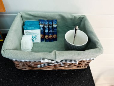 Tık, İrlanda - 22 Ekim 2025: Yeşil kumaşla kaplanmış örülmüş sepet çay kesesi ve sıcak bir sabah için bir fincan.