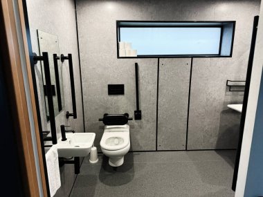 Tık, İrlanda - 22 Ekim 2025: Knock Ireland 'da çağdaş gri banyo içinde bir duvar lavabosu, tuvalet, siyah eşyalar ve büyük bir pencere var..