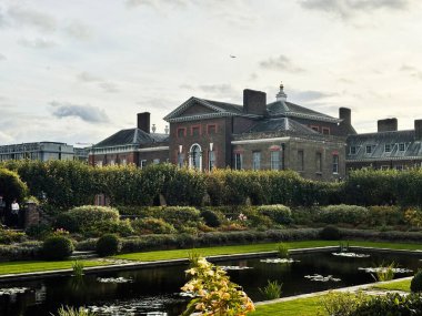 Londra, İngiltere - Ekim 05, 2025: görkemli tuğla Kensington Sarayı, manikürlü bahçeler, yansıtıcı bir gölet ve Londra 'da İngiliz manzarası.