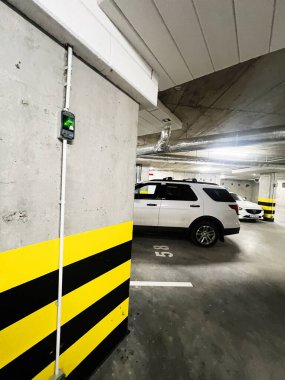 Rzeszow, Polonya - 25 Ekim 2025: Modern bir yeraltı otoparkı parlak güvenlik şeritlerinin yakınına park edilmiş beyaz bir Ford Explorer SUV gösteriyor.