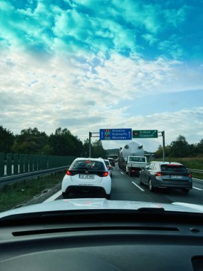 Krakow, Polonya - 25 Ekim 2025: Mavi yönlü ve yoğun trafik işaretli kalabalık bir Polonya otoyolu parçalı bulutlu bir gökyüzü altında.