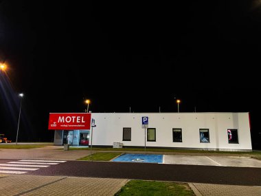 Krakow, Polonya - 25 Ekim 2025: Çağdaş bir motelin gece vakti dış mekanı, sokak lambalarıyla aydınlatılmış, park yeri ve ulaşılabilirlik özellikleri gösteriliyor.