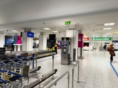Manchester, İngiltere - 07 Kasım 2025: Manchester havaalanı bavul, yük arabaları ve servis masaları ve tabelalarında gezginlerle dolu.
