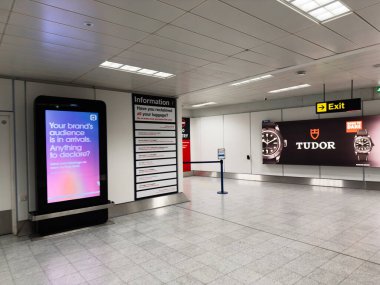 Manchester, İngiltere - 07 Kasım 2025: Manchester 'da bilgi panosu, dijital reklam ekranı ve bir Tudor saat pankartı bulunan kamusal alan.