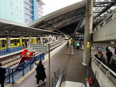 Manchester, İngiltere - 07 Kasım 2025: Sarı trenler, açık tabelalar ve yoğun bir istasyonda bekleyen yolcularla dolu Manchester platformu.