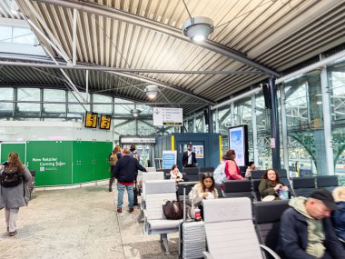Manchester, İngiltere - 07 Kasım 2025: Manchester 'daki parlak, çağdaş bir terminalde oturan yolcular, uçuş ve seyir tabelalarını bekliyorlar.