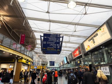 Manchester, İngiltere - 07 Kasım 2025: Gezginler, bavullar, dijital panolar ve perakende mağazaları ile kalabalık Manchester İngiltere havaalanı salonu.