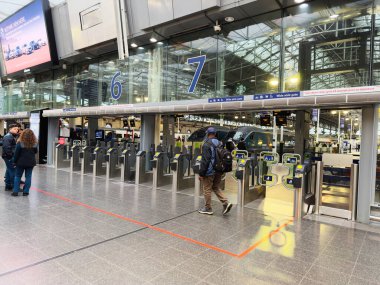 Manchester, İngiltere - 07 Kasım 2025: Manchester istasyonundaki yolcular modern bir merkezde 6. ve 7. platformların yakınlarındaki kapılardan geçtiler.