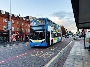 Manchester, İngiltere - 08 Kasım 2025: Mavi bir çift katlı otobüs Manchester caddesinde dükkan ve yayalarla dolanıyor.