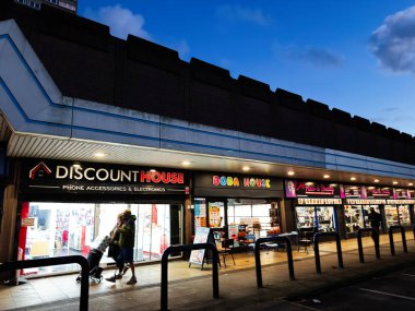 Salford, İngiltere - 08 Kasım 2025: Salford 'da indirimli bir mağaza, lokantalar ve akşam müşterileri içeren işlek bir alışveriş caddesi.